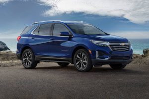 A blue 2022 Chevrolet Equinox parked on the pavement with the ocean in the background. 